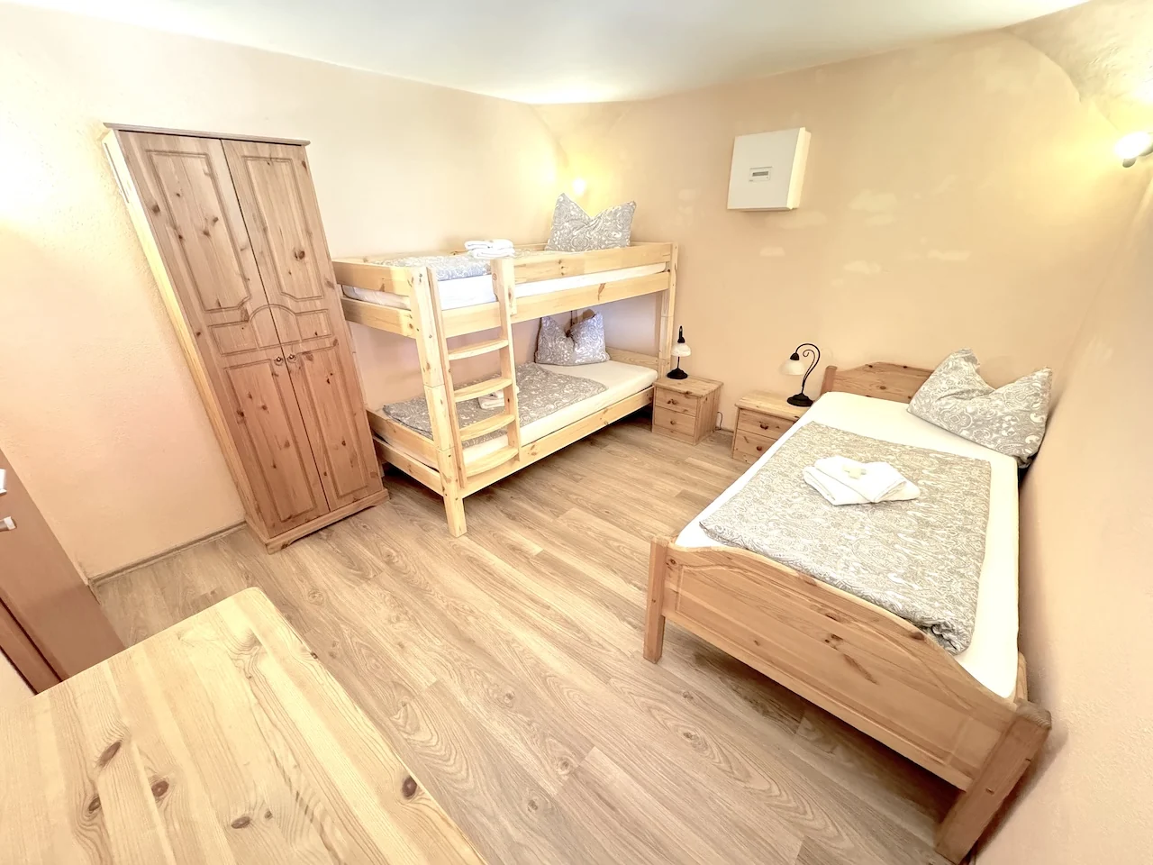 Dreibettzimmer auf der Laurent Ranch in Gottfrieding mit Etagenbett und Einzelbett aus hellem Holz