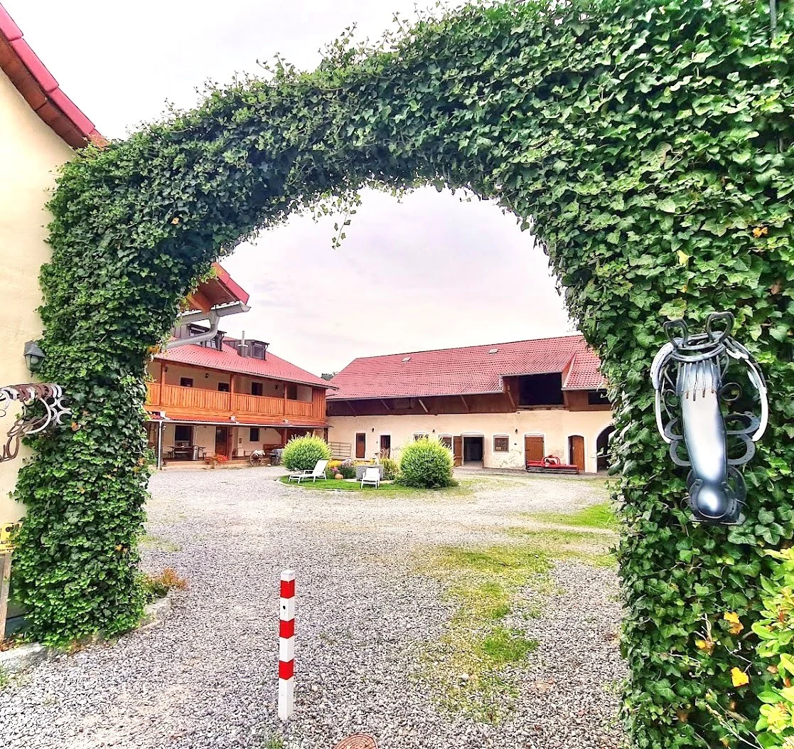 Efeu-bewachsener Torbogen mit Blick in den Kieshof der Laurent Ranch in Gottfrieding